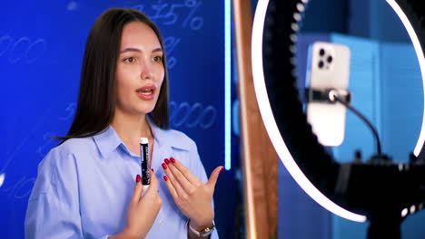 dynamic online talk by a young woman. a young woman wears a blue shirt while presenting confidently to an audience through a ring light setup