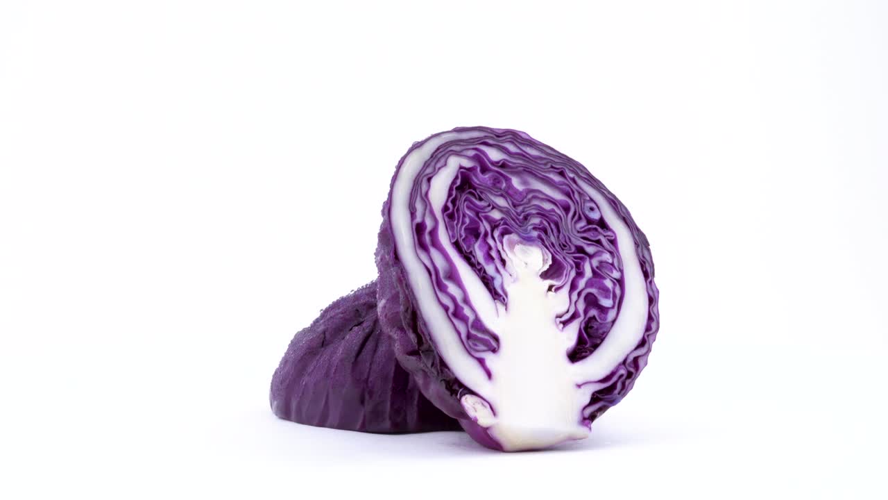 dos mitades de mini repollo púrpura con gotas de agua. corte cruzado. girando en la mesa giratoria aislada en el fondo blanco. primer plano. macro.