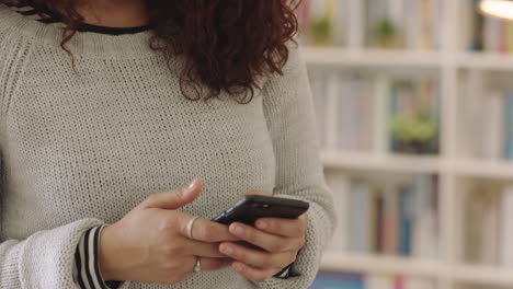 close up young mixed race woman using smartphone texting messaging smiling enjoying mobile phone social media communication in home study library