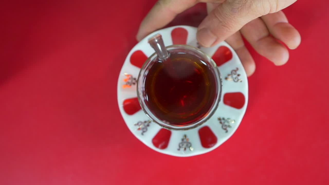 빨간색 배경에 차가 가득한 컵과 코스터