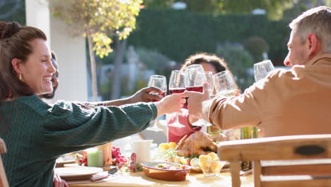 Felices-Y-Diversos-Amigos,-Hombres-Y-Mujeres,-Brindando-En-La-Comida-De-Celebración-En-El-Soleado-Jardín.