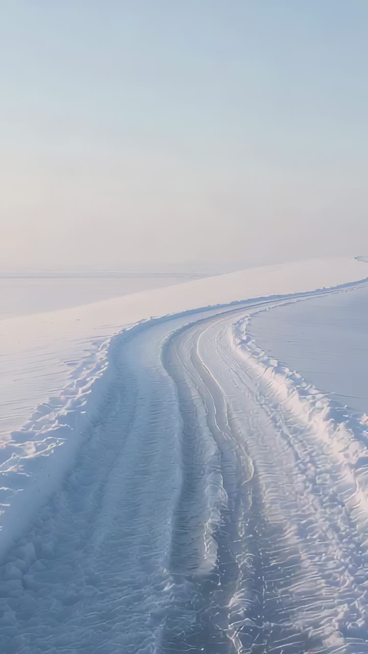 Vertical video: Moving camera sliding along curving ice track on open plain, showing grooves
