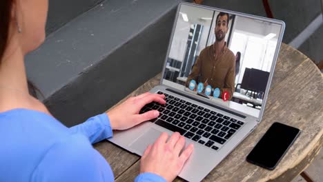 mujer caucásica haciendo una videollamada en el portátil con un colega de oficina masculino