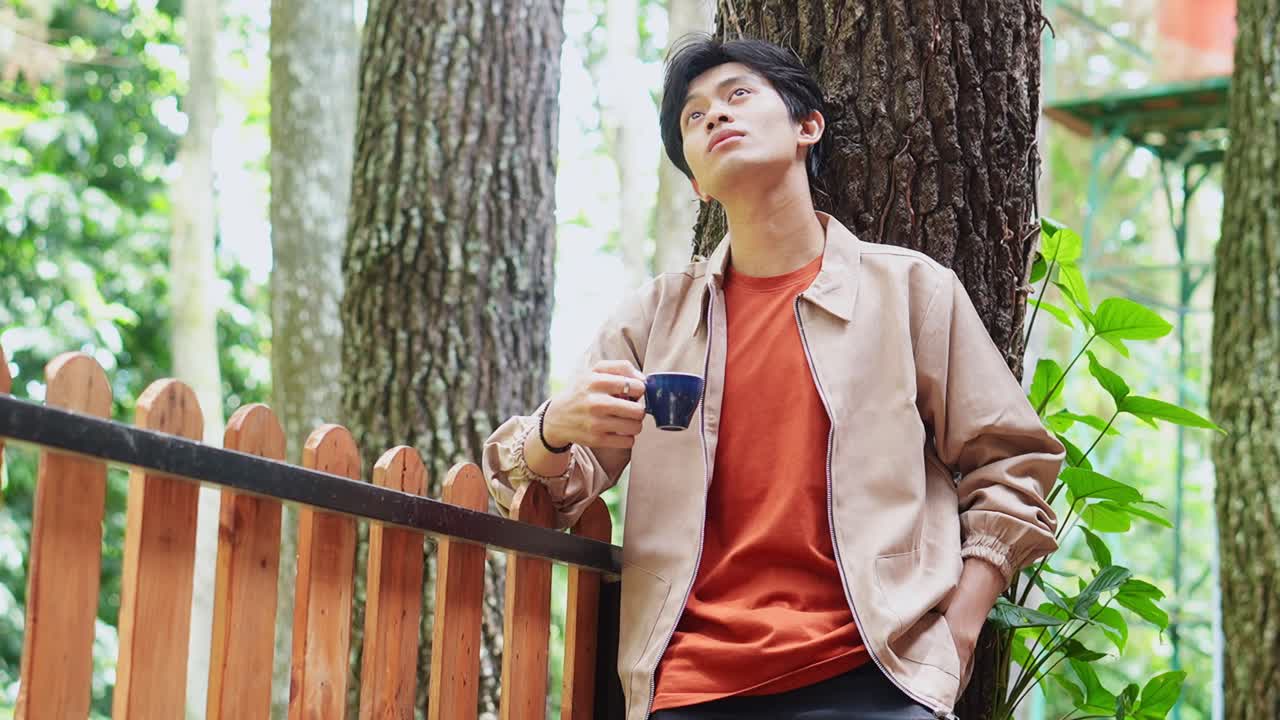 Young asian man enjoying morning coffee at cafe outdoors
