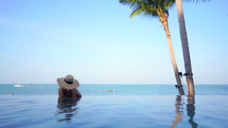 Woman-enjoying-beautiful-seascape-tropical-ocean-view-from-infinity-swimming-pool