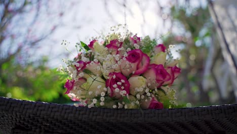 A-beautiful-wedding-bouquet-of-mixed-flowers-laying-on-latticed-surface-outdoors-against-the-sun