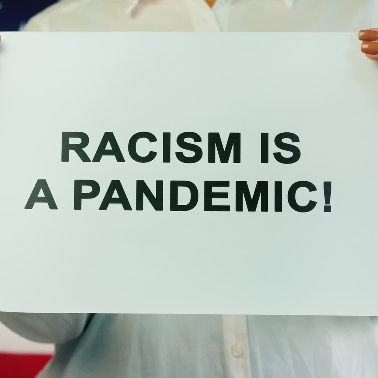 mujer sostiene un cartel que dice que el racismo es una pandemia en el fondo de la bandera estadounidense