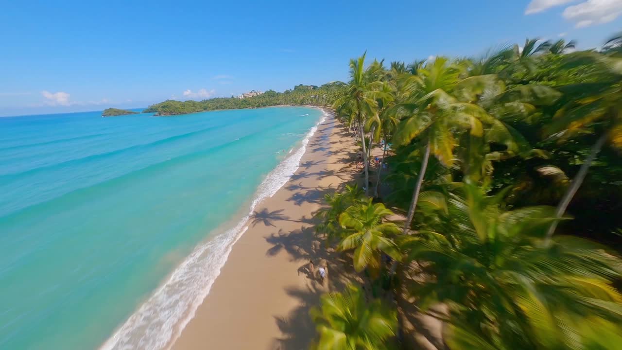 vuelo aéreo fpv sobre palmeras tropicales resort con playa dorada a lo largo del mar caribe de color turquesa a alta velocidad - hermoso día soleado en la isla de república dominicana con hotel de lujo