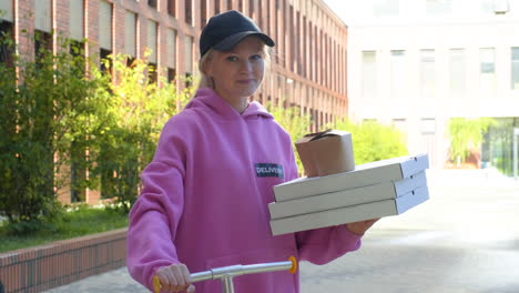 young woman holding pizza boxes at the street