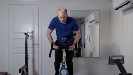 middle aged caucasian man workout on bike in home-gym, front view