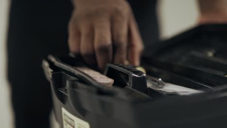 Close-up-black-man-hands-unlocking-toolbox.-Man-worker-hands-taking-screw