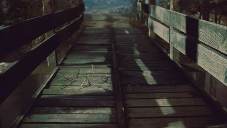 weathered wooden bridge leads into serene rural landscape at dusk