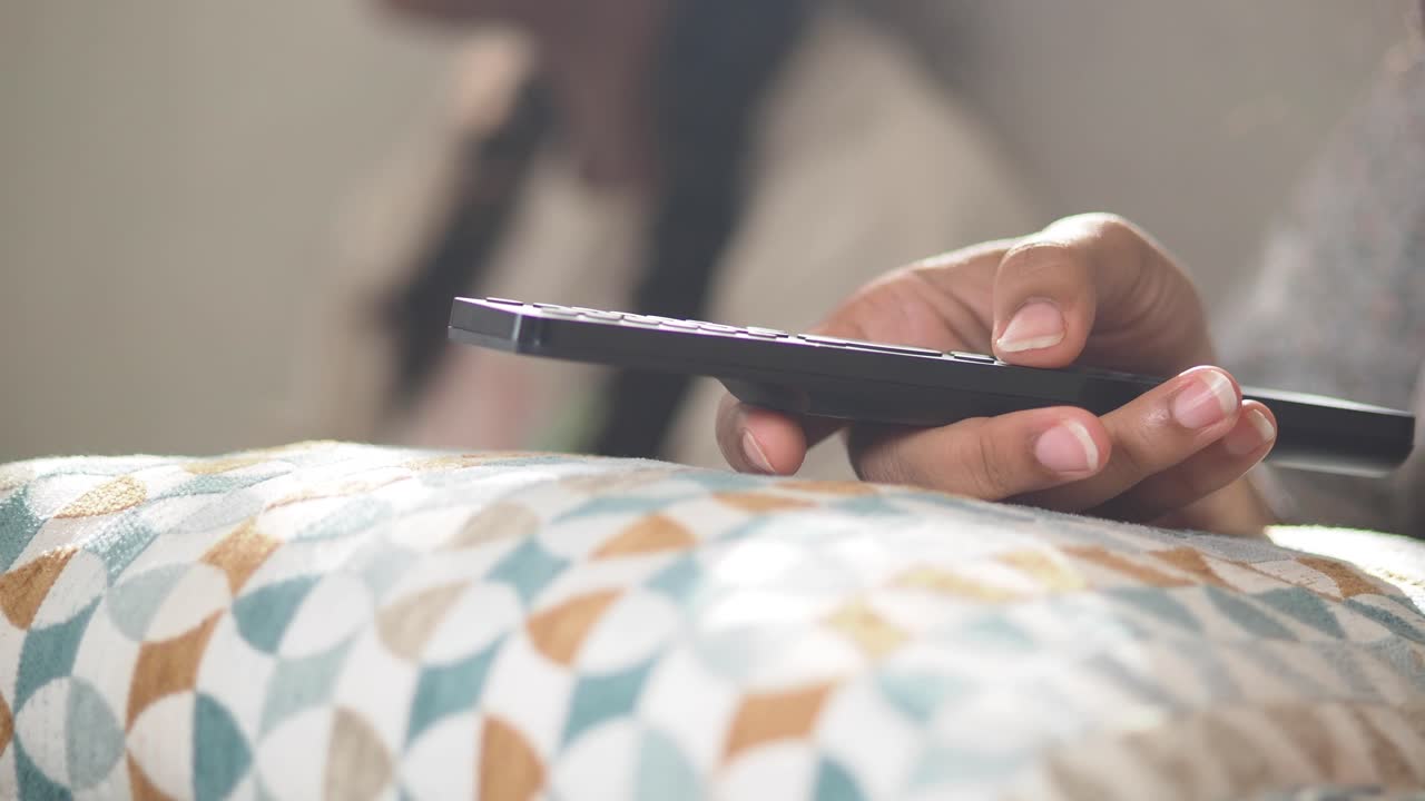 Mano che tiene un telecomando su un cuscino