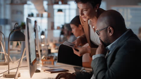 business-people-working-late-using-computer-team-leader-woman-sharing-information-with-colleague-giving-feedback-discussing-solution-for-project-deadline-in-office-at-night