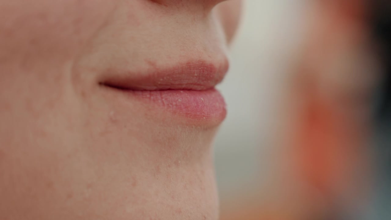 Close up view of woman lips as woman applies lip balm showing texture and care process in detail. focus remains on her facial features with soft lighting highlighting natural skin details
