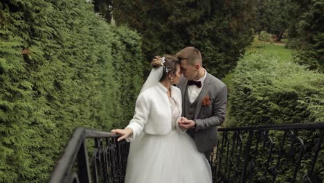 Newlyweds,-caucasian-groom-with-bride-stay-on-stairs-in-park,-wedding-couple,-man-and-woman-in-love