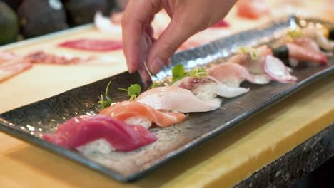 chef de sushi coloca brotes de guisantes como decoración en un plato tradicional de nigiri, cierre hd