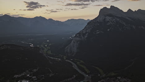 banff ab canada aerial v8 high altitude drone flyover town center capturing forested valley, bow river course and mountain ranges at sunrise in the summer - shot with mavic 3 pro cine - july 2023