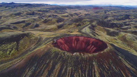 stunning aerial view of a vibrant red crater in a volcanic landscape