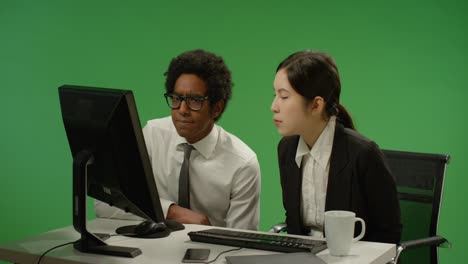 녹색 화면에 있는 컴퓨터를 걱정하는 두 동료