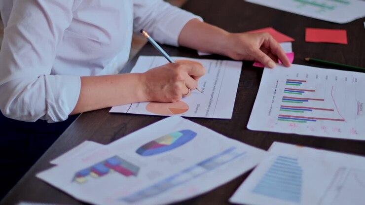 Woman writing on a paper with a graph on it at a desk, in an office