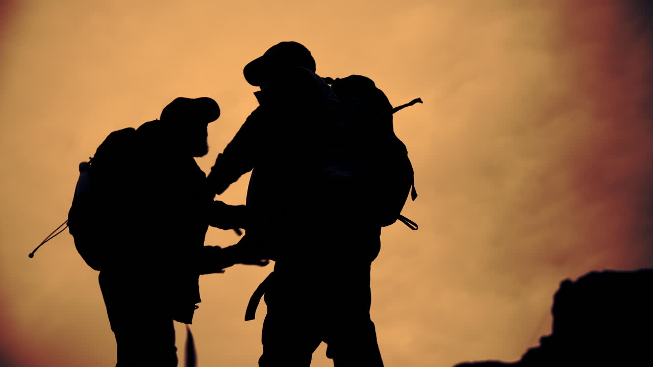Silhouettes of hikers with backpacks at sunset