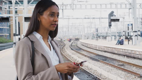 Geschäftsfrau-Pendelt-Mit-Mobiltelefon-Auf-Dem-Bahnsteig-Zur-Arbeit