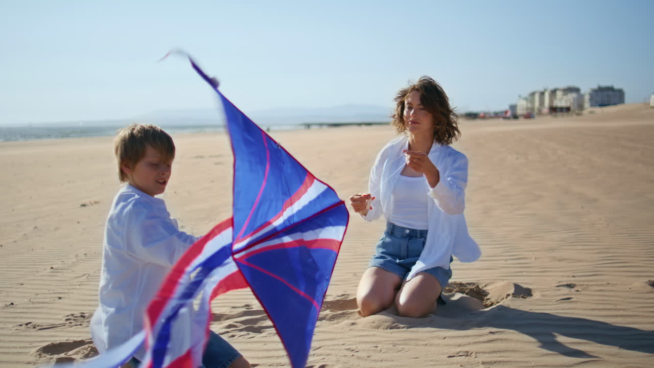 Mother playing boy kid kneeling on sandy sunny beach. Caring mom teaching child