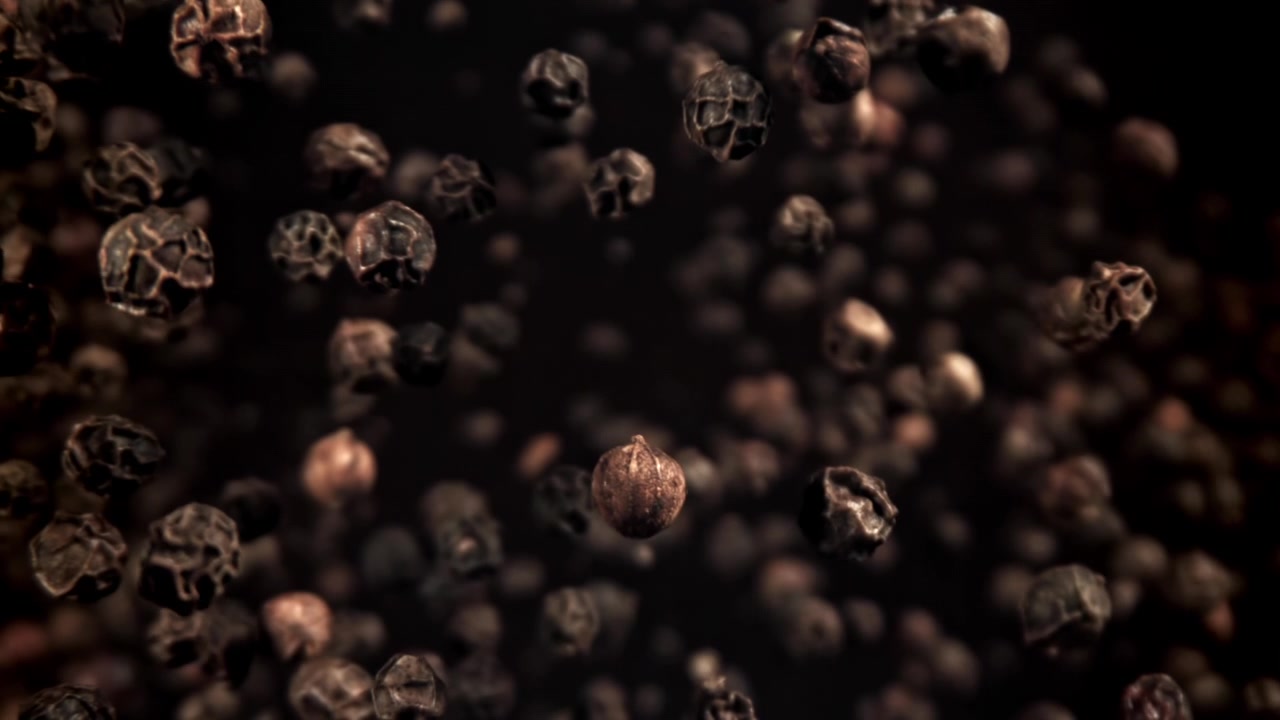 Svarte pepperkorn flyter og kommer i fokus i sakte film