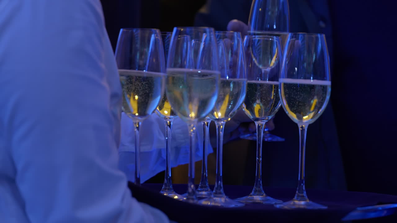 Cameriere che distribuisce bicchieri di champagne agli ospiti durante una serata evento, al rallentatore