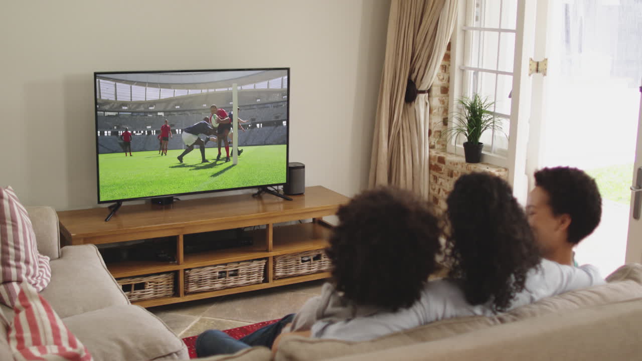 Famiglia felice seduta a casa insieme che guarda una partita di rugby in TV