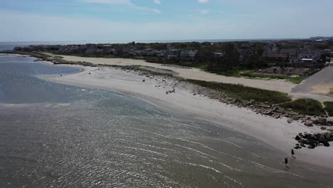 An-aerial-view-of-the-waters,-facing-an-empty-beach-on-a-sunny-day-in-the-summer
