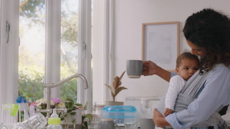 happy mother holding baby at home tired mom drinking coffee relaxing after housework washing dishes in kitchen