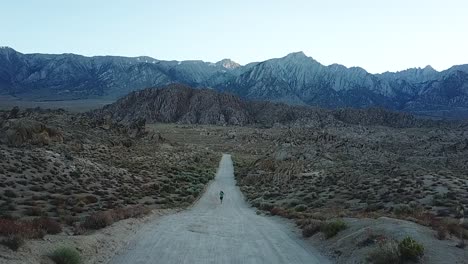 lonely man running on desert road under alabama hills, california usa, slow motion aerial view