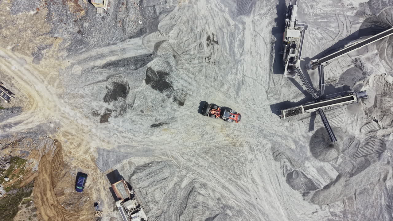 Granite quarry operation showing large machines, trucks, and heavy equipment at work in an active mining area