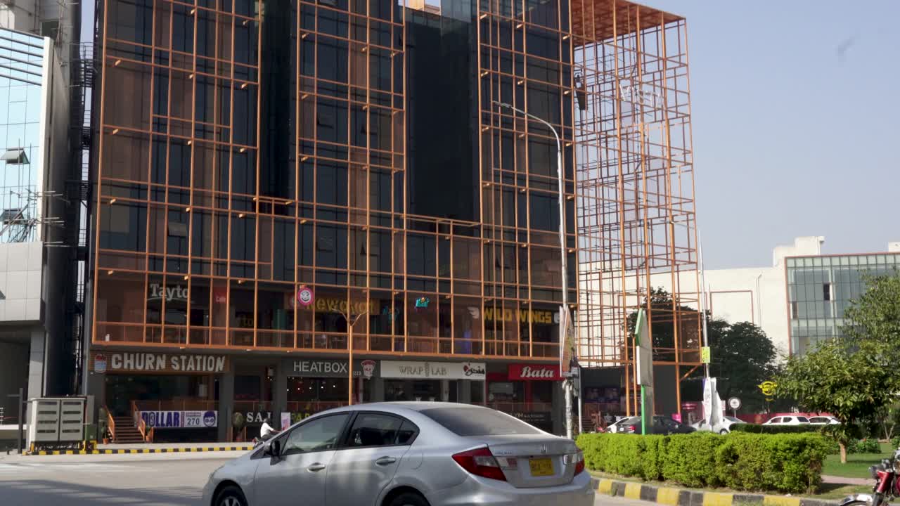 Behold the stunning view of a bustling street lined with towering commercial edifices, exuding their magnificence as cars speed by.