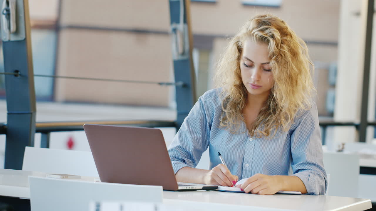 attraktiv ung kvinde, der arbejder på byggepladsen om sommeren. kaye bruger bærbar computer og tager noter i en notesbog.