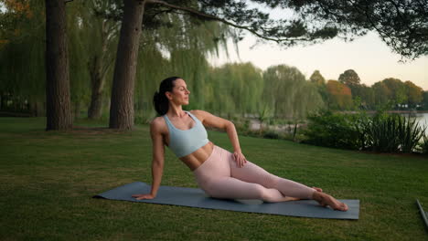 woman practicing yoga on a mat in a park setting