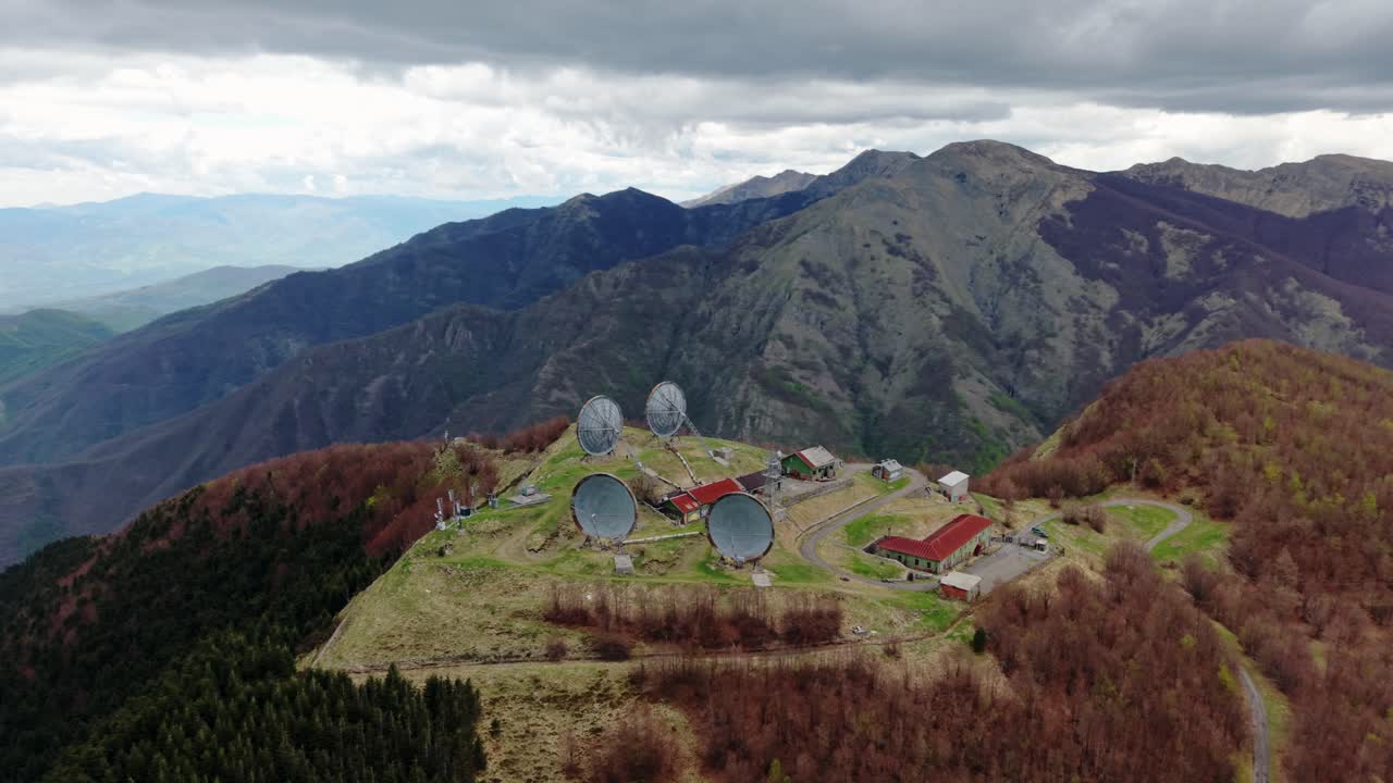 Old radar station on mountain top seen from above, moody skies and remote landscape