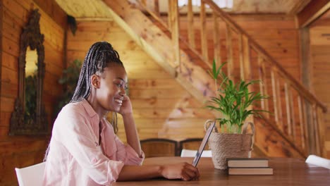 Glückliche-Afroamerikanische-Frau,-Die-Am-Tisch-Sitzt-Und-Laptop-Für-Videoanrufe-Nutzt,-Zeitlupe