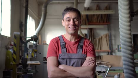 a happy male carpenter smiling confidently in his woodworking workshop