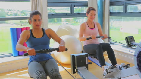 mujeres en la máquina de remo apoyadas por un entrenador
