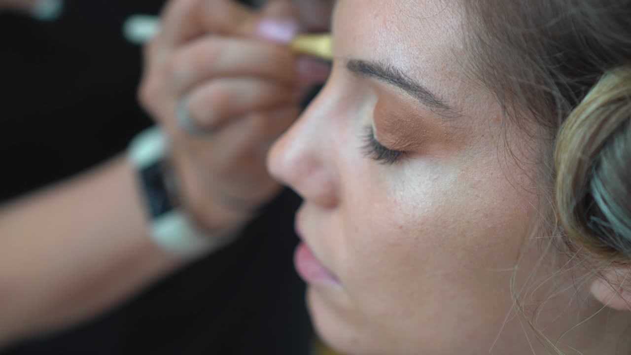 artista de maquillaje pintando los párpados de la novia