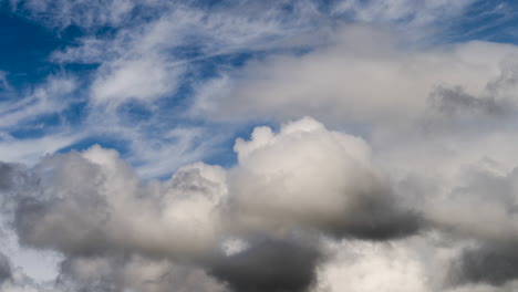 cloud time lapse with white fluffy mixing with dark angry clouds swirling around in blue sky