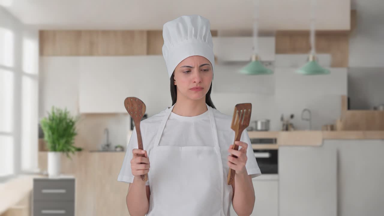 Indian female professional chef posing with spoon and spatula
