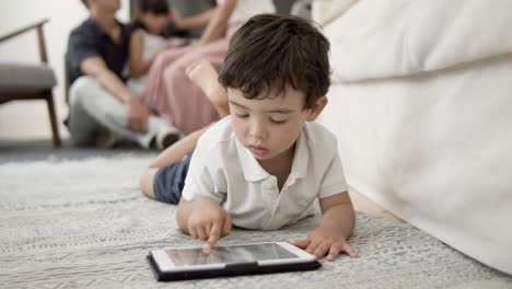 Süßer-Kleiner-Junge-Mit-Tablet,-Der-Auf-Dem-Boden-Im-Wohnzimmer-Liegt