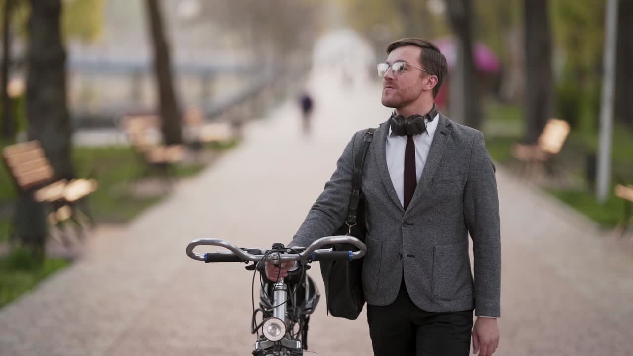 잘생긴 젊은 사업가 공원과 미소에 자전거와 함께 간다