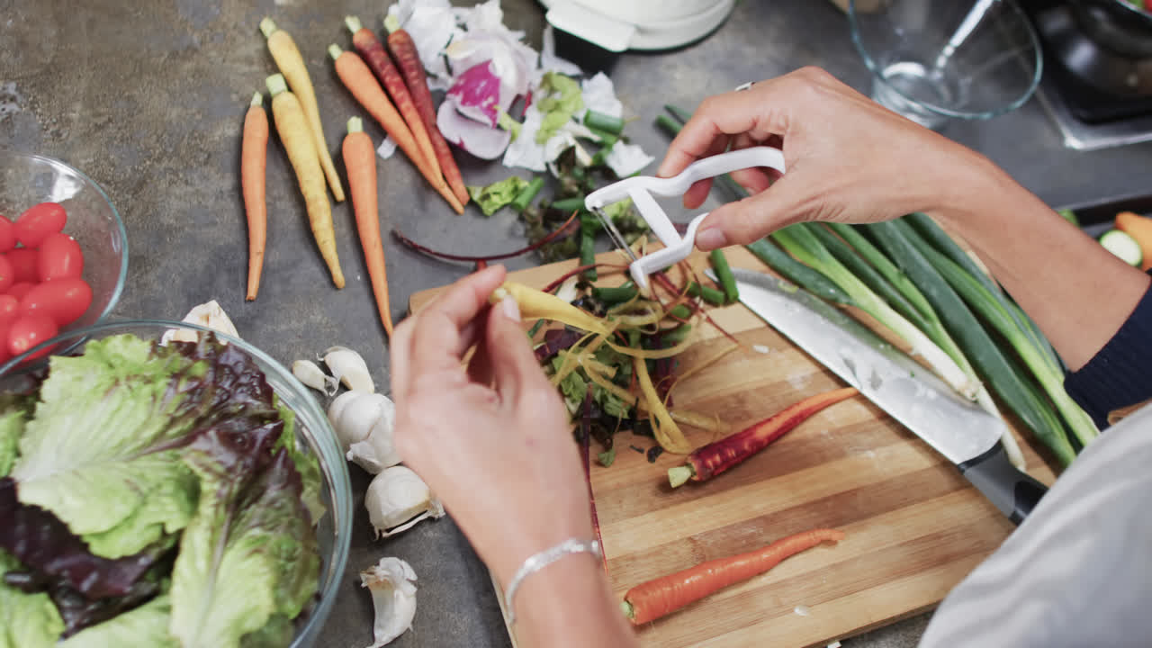 부에서 채소 질을 벗기는 두 인종 여성의 손, 느린 동작