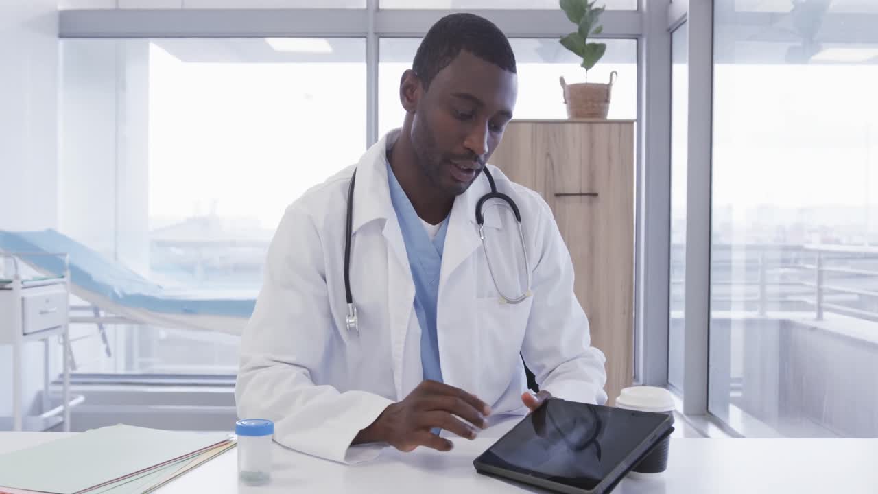 African american male doctor using tablet and making video call in hospital, slow motion