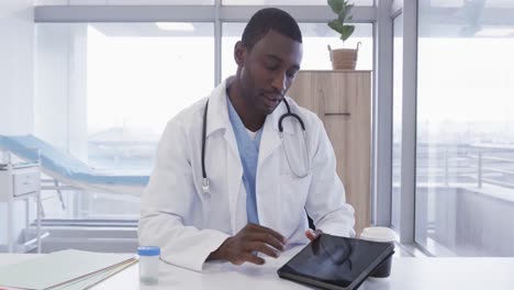 African-american-male-doctor-using-tablet-and-making-video-call-in-hospital,-slow-motion